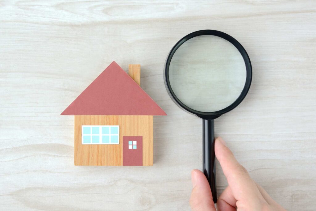 A magnifying glass and a house figure resembling inspecting your property for pests.