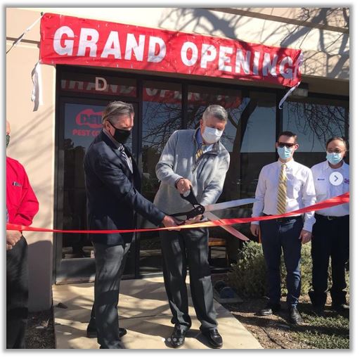 Dewey Pest Control employees cutting ribbon at grand opening ceremony.